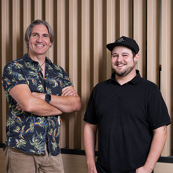 Two people standing side by side in front of a wooden wall – a moment of collaboration and diversity at HOBART.
